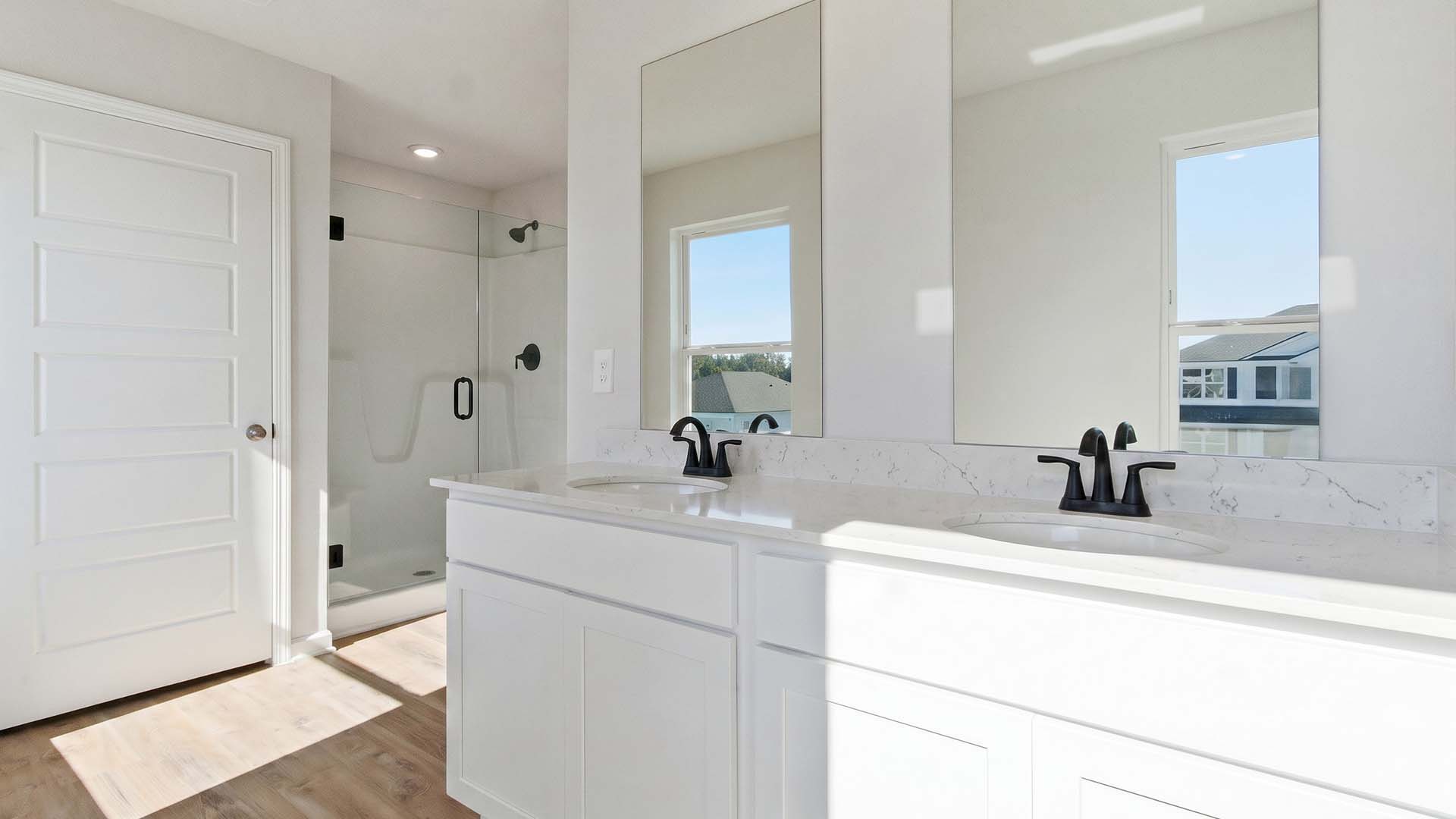 The vanity has lower cabinetry and drawers for storage. The shower has a frameless glass enclosure