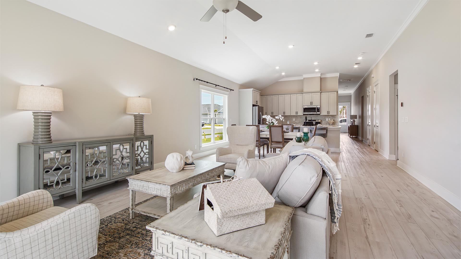 Open living area with kitchen and dining room and living room with EVP flooring and large windows and ceiling fan.