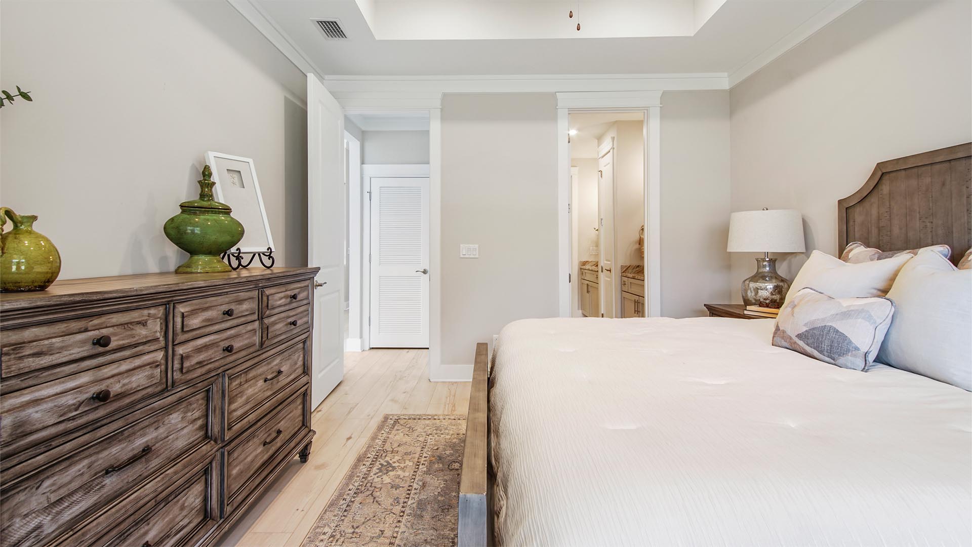 Primary bedroom with EVP flooring and vaulted ceiling and primary bathroom entrance.