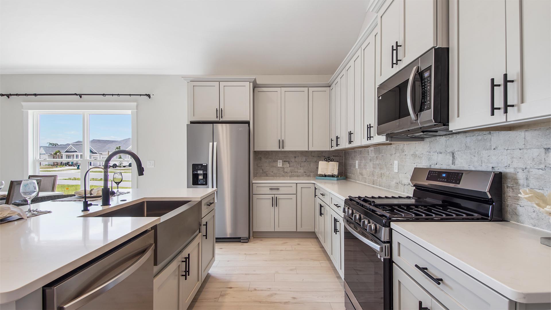 Open kitchen with stainless-steel single basin undermount sink and quartz countertops and EVP flooring.