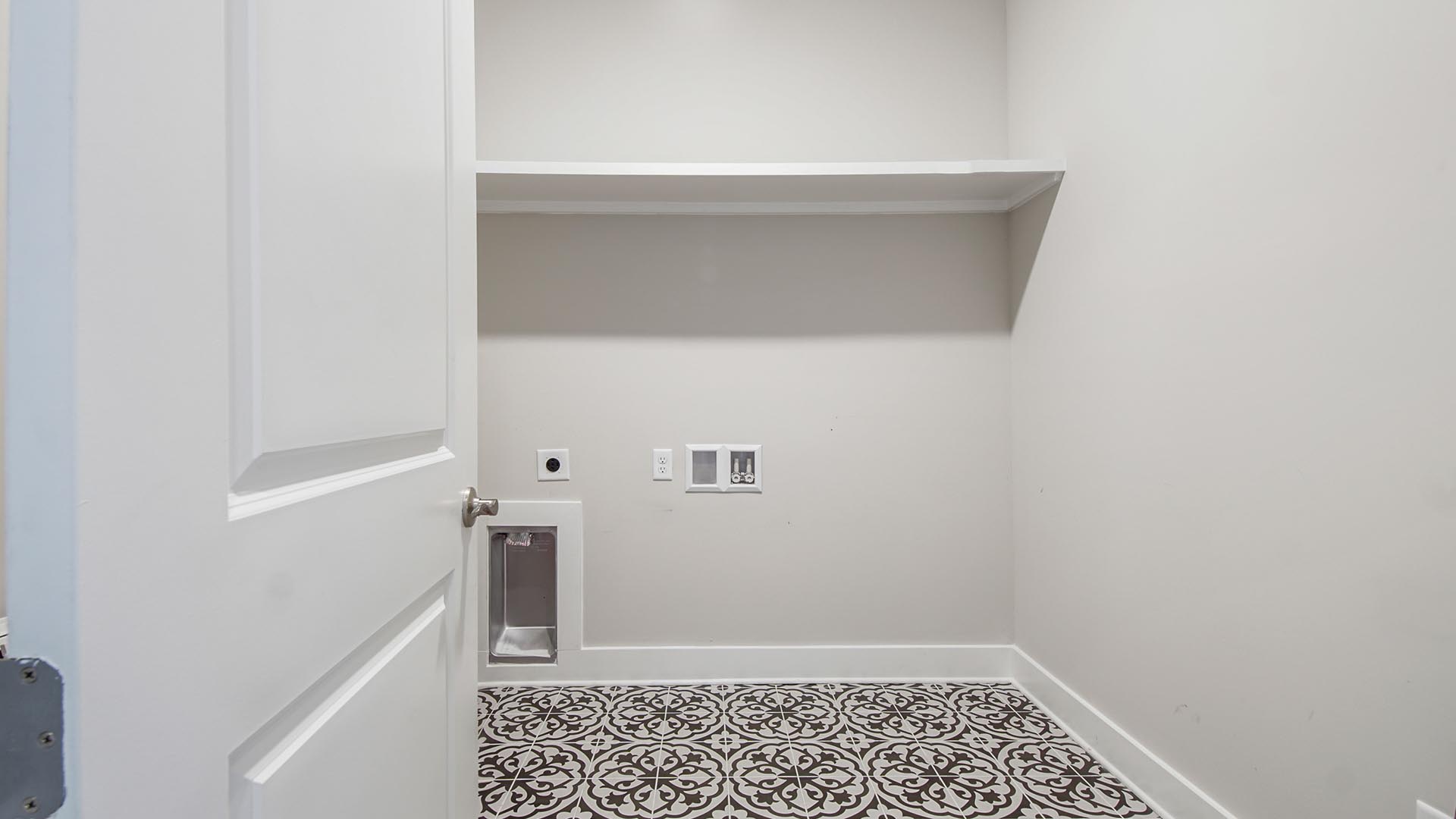 Laundry room with accent floor and wood shelving.
