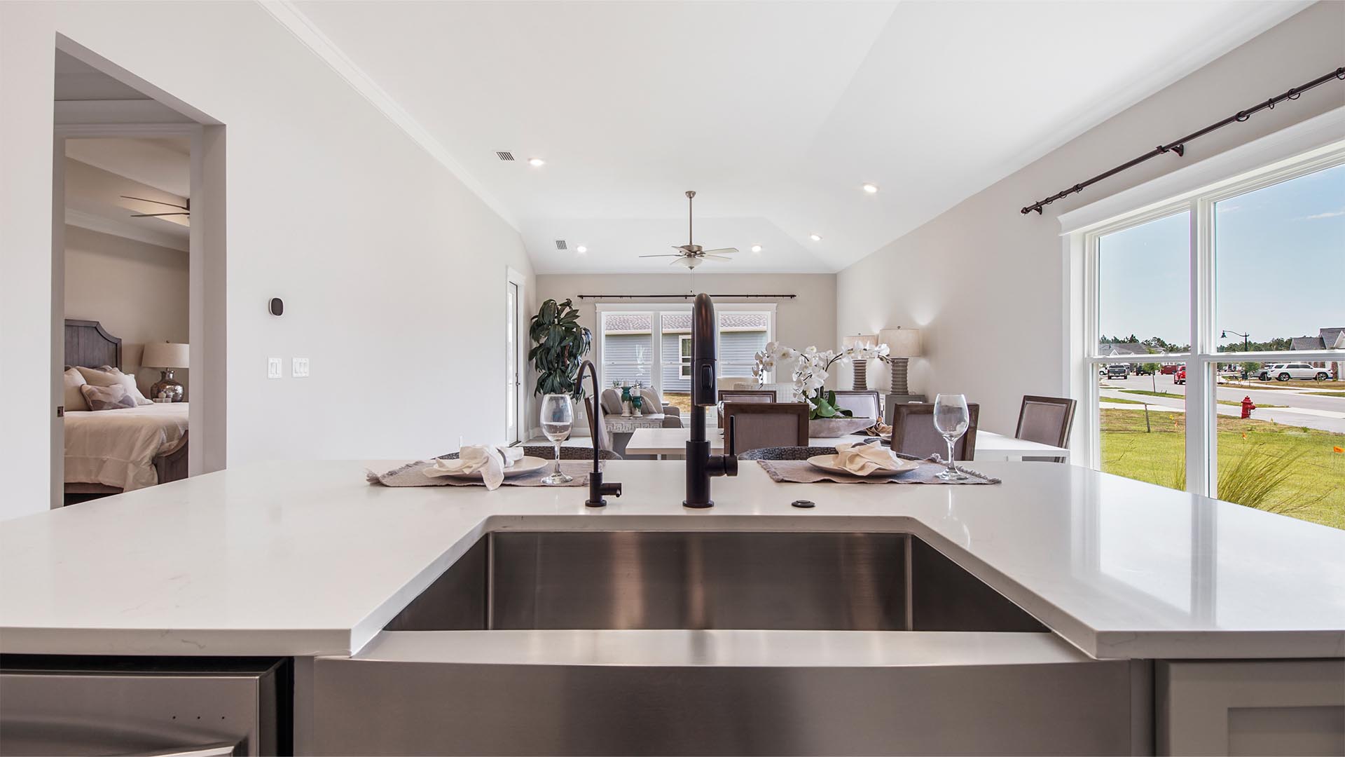 Large kitchen island overlooking living area with stainless-steel single basin undermount sink and quartz countertops.