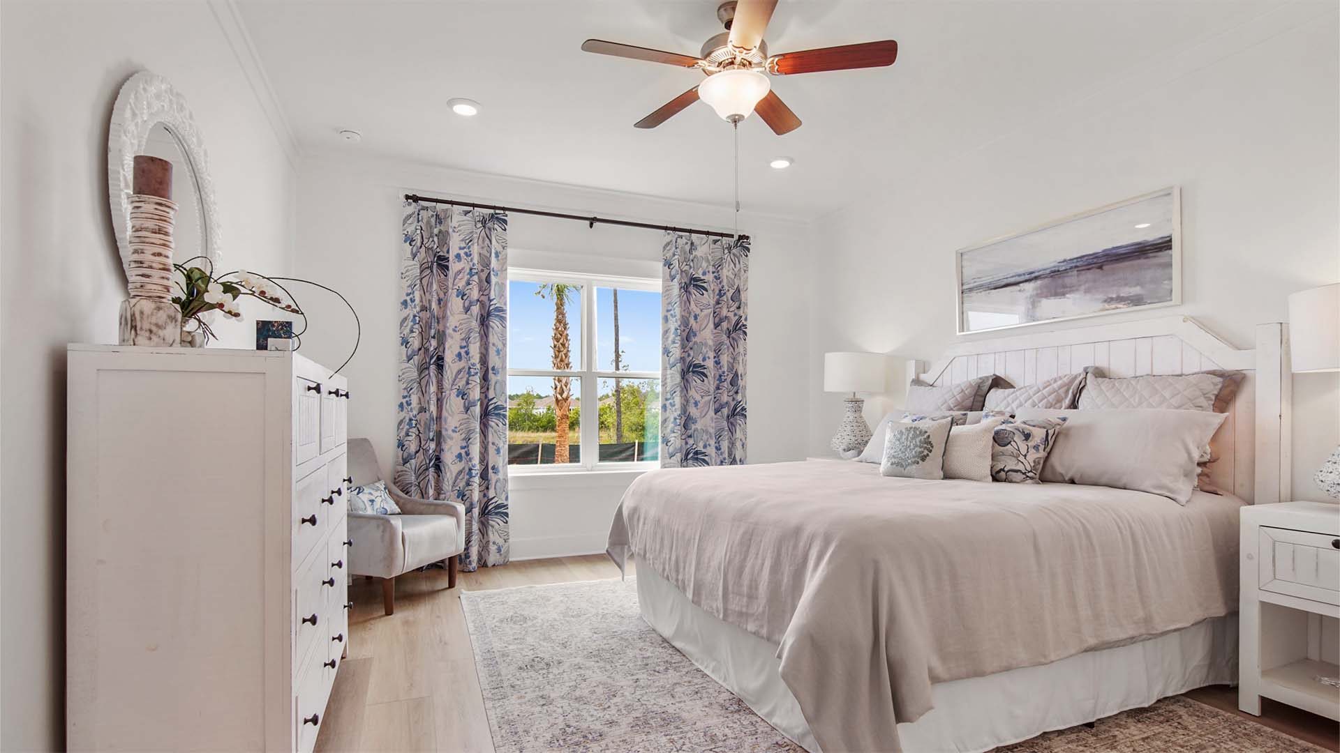 Primary bedroom with EVP flooring and a large window and ceiling fan.