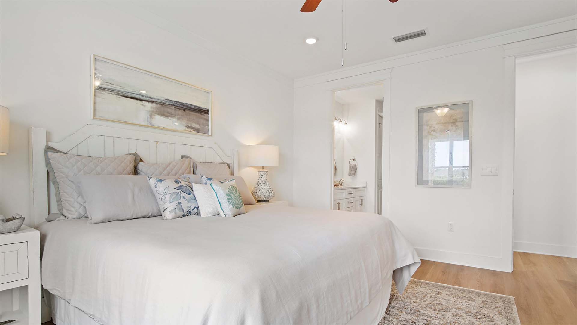 Primary bedroom with EVP flooring and ceiling fan and entrance to bathroom.