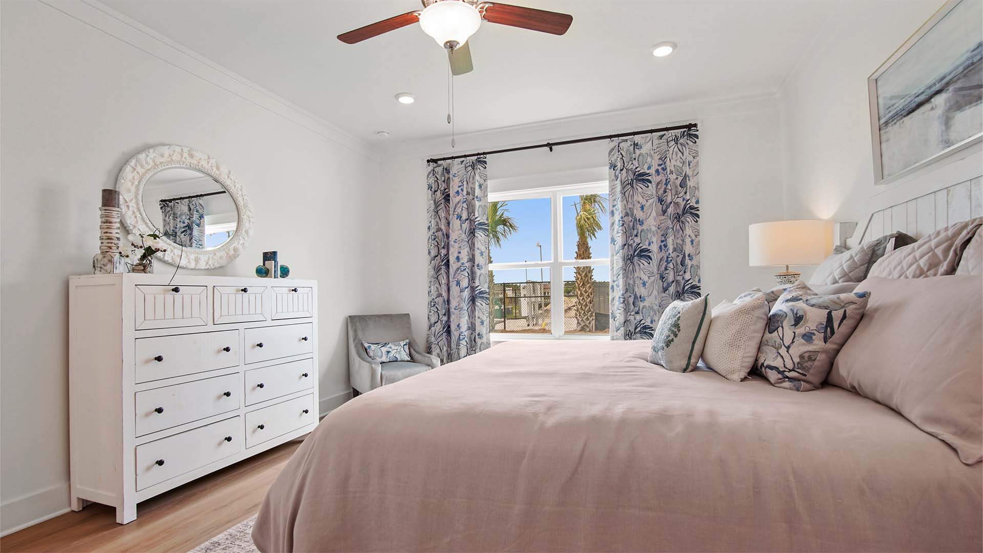 Primary bedroom with EVP flooring and a large window and ceiling fan.