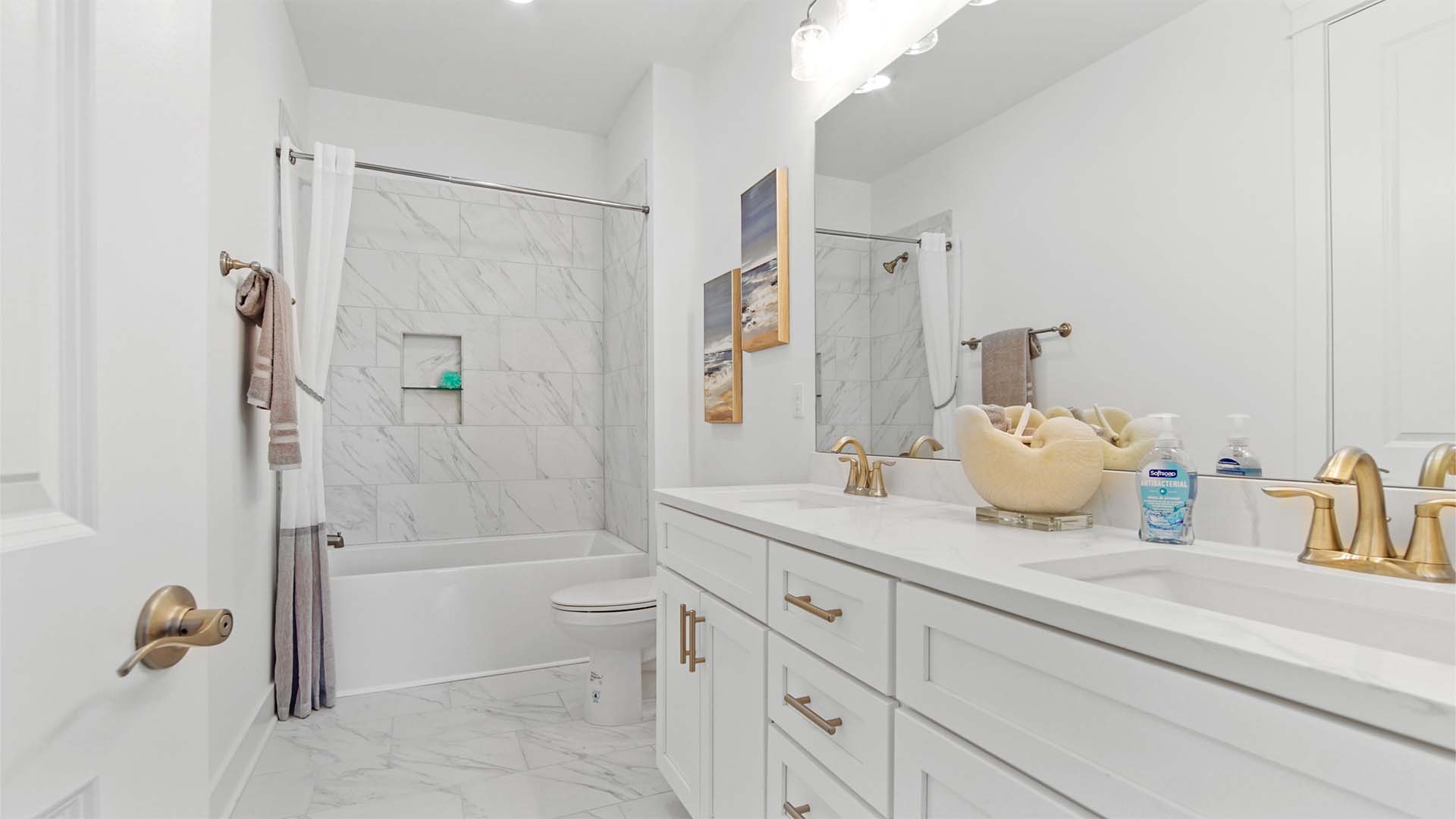 Bathroom three with dual vanity and quartz countertops and shower tub combo with tile walls.