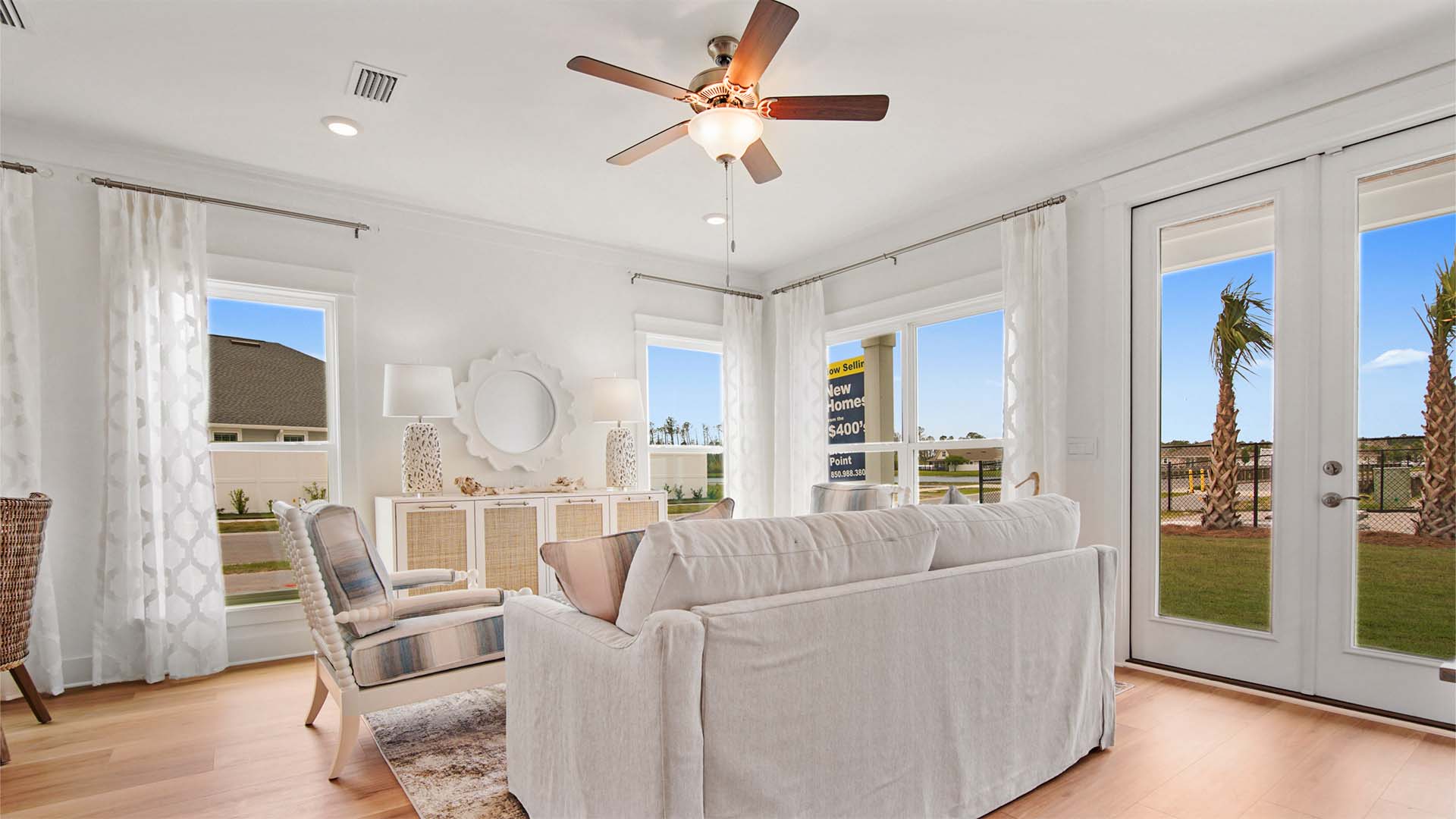 Living area with EVP flooring and large windows and ceiling fan and glass double back doors to back patio.