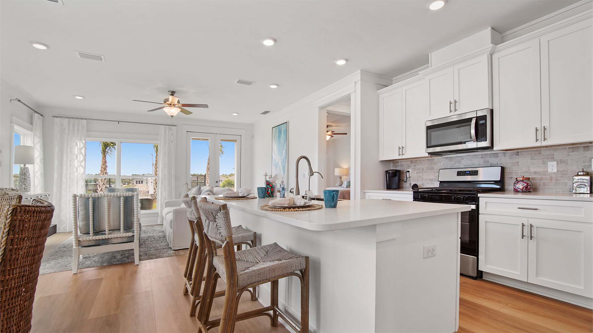 Kitchen with large center island and quartz countertops and white cabinetry and stainless-steel appliances.