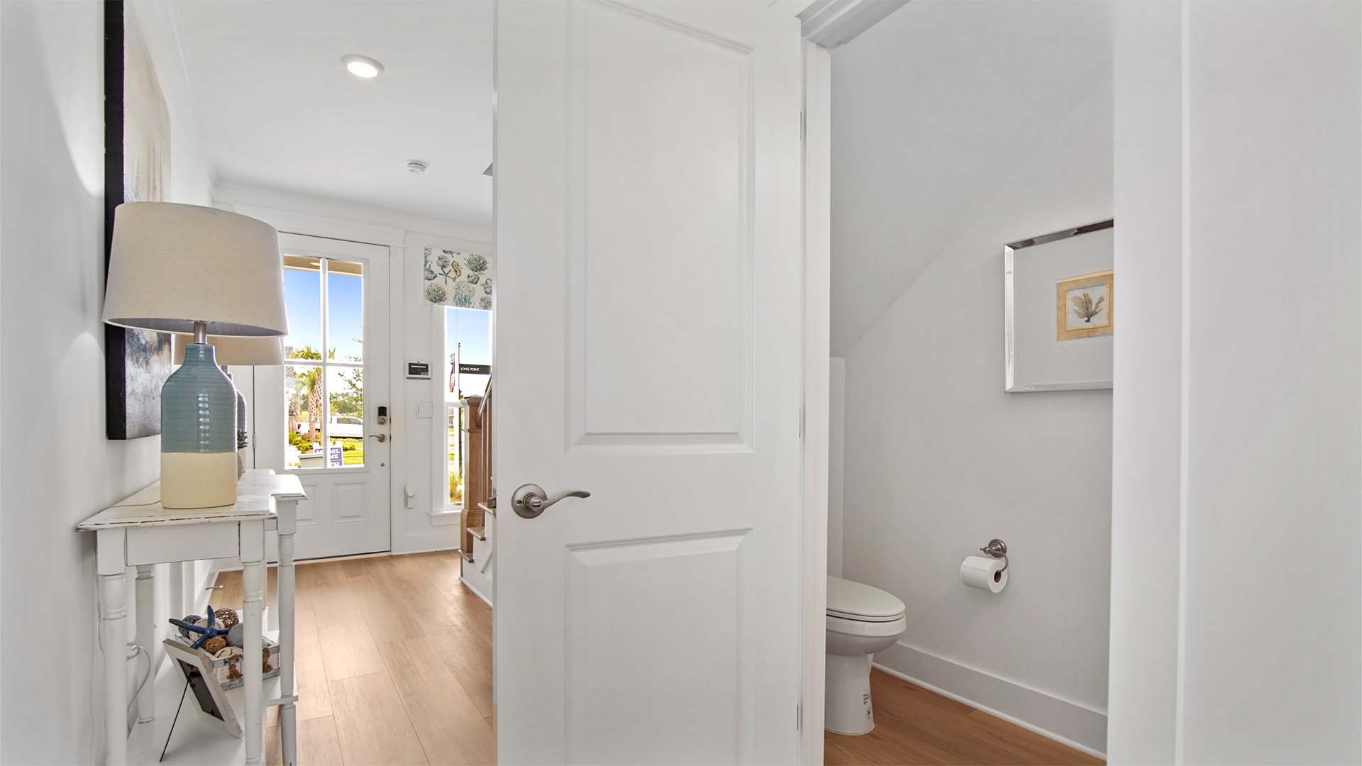 Half bathroom with EVP flooring in hallway to front door and stairs.