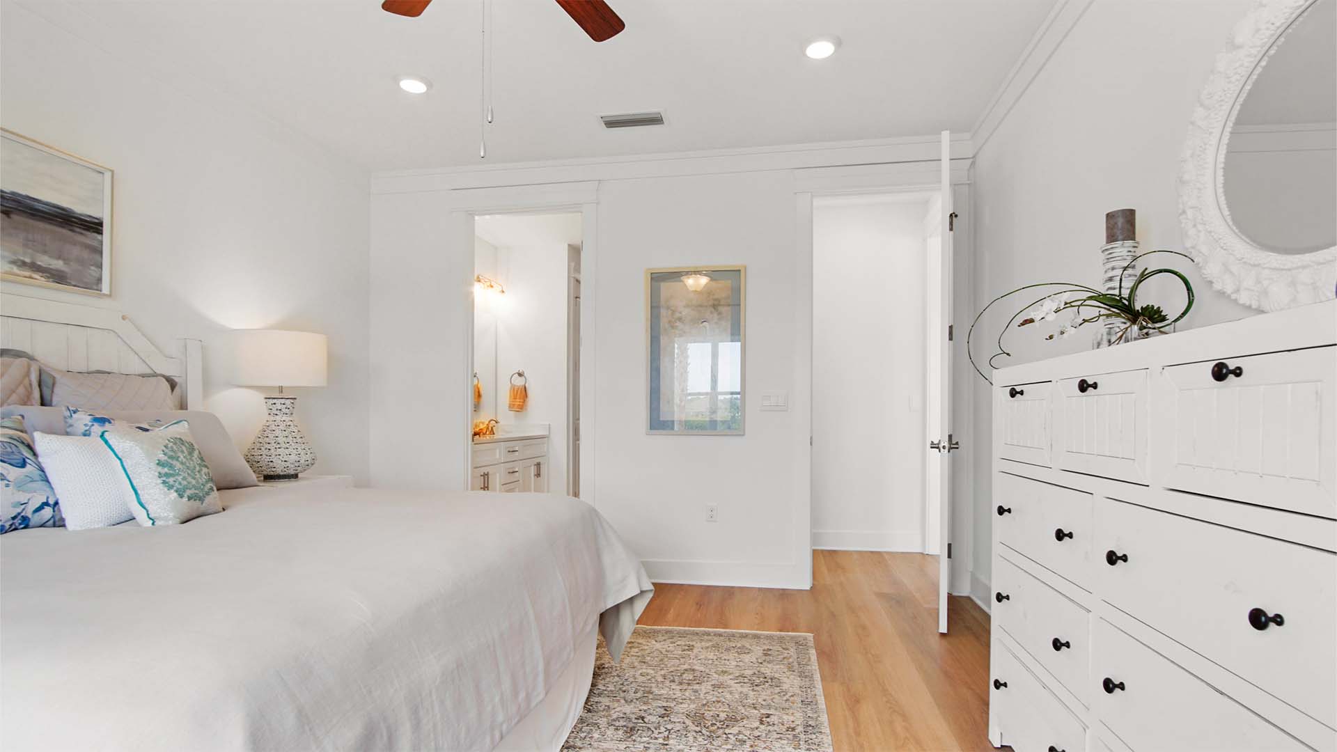 Primary bedroom with EVP flooring and ceiling fan and entrance to bathroom.