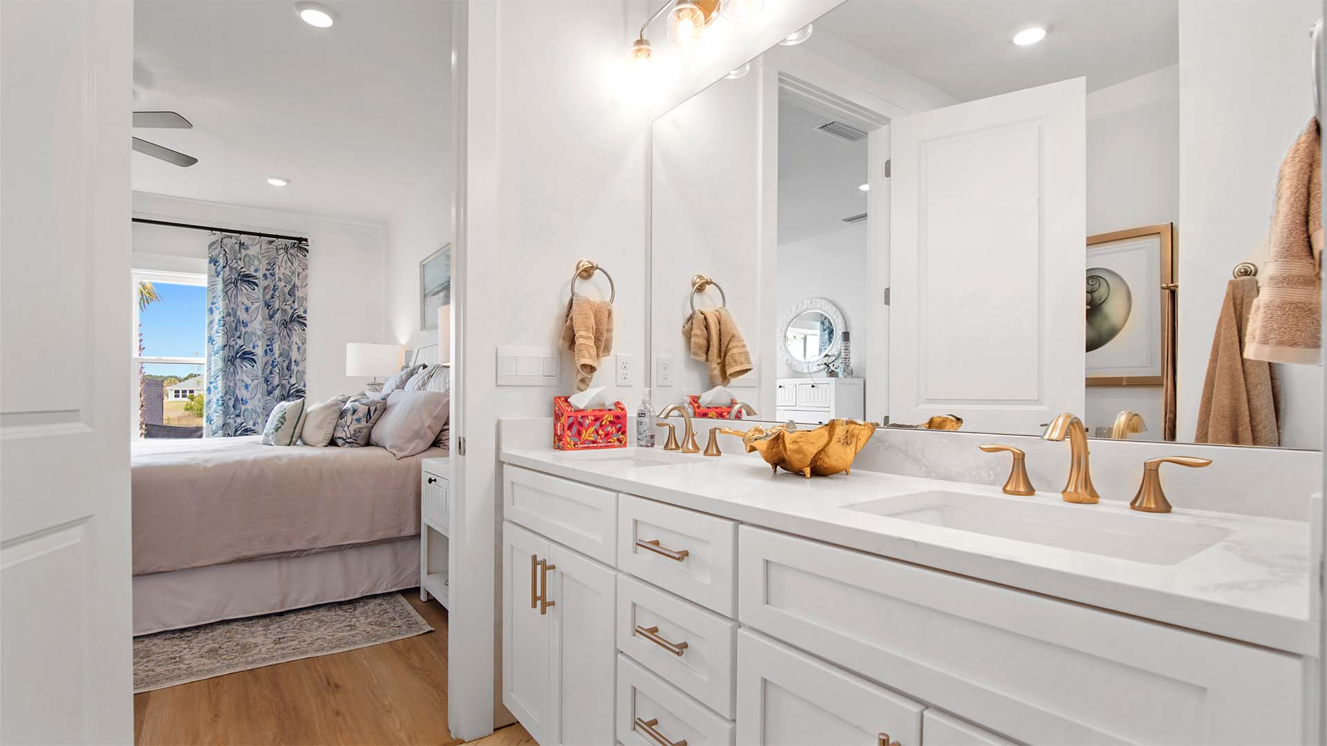 Primary bathroom with dual vanity and quartz countertops and white cabinetry and large mirror.