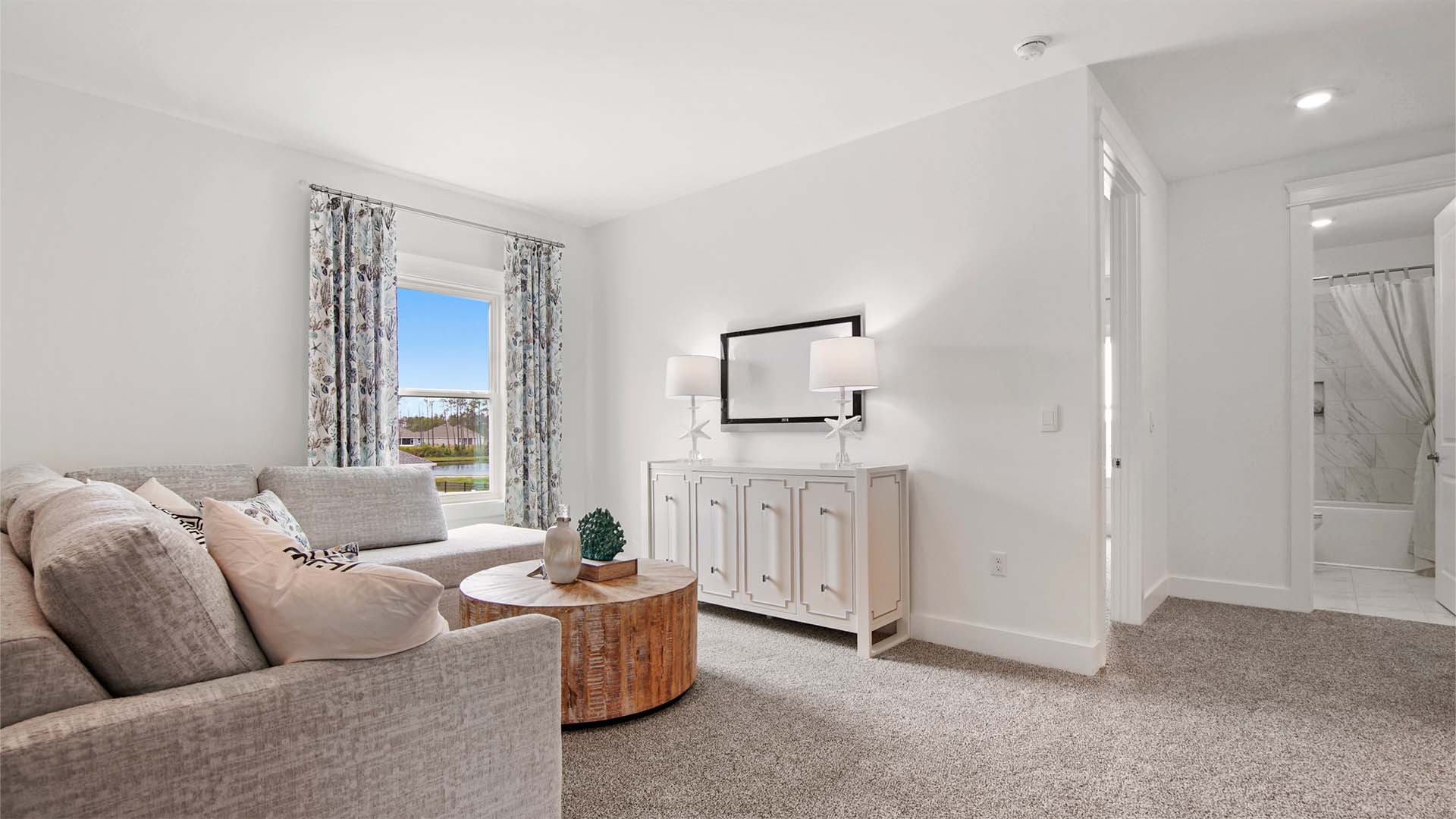 Upstairs family room with carpet flooring and a window and next to hallway to guest bedrooms and bathrooms.