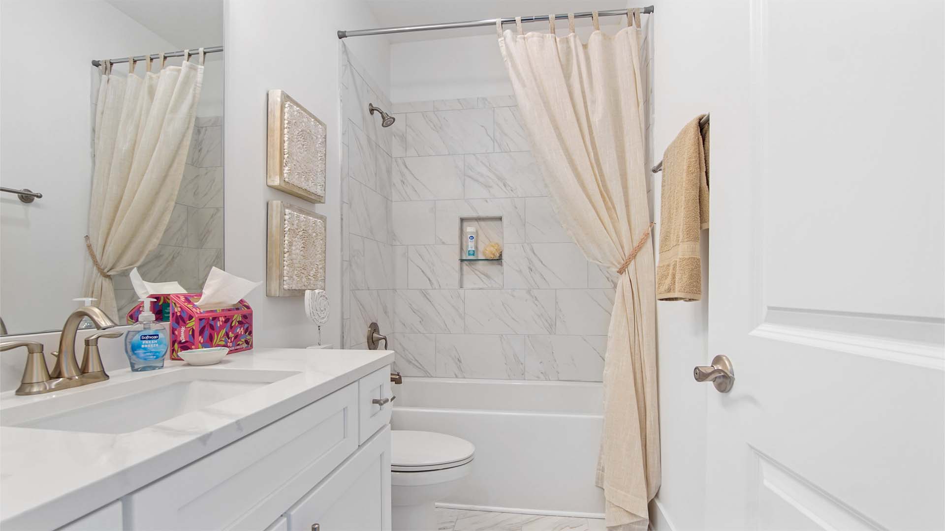 Bathroom two with shower tub combo with tile wall and a single vanity with quartz countertops and marbled tile flooring.