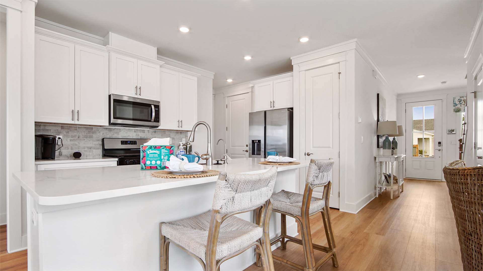 Open concept kitchen with EVP flooring and bar seating and white cabinetry and stainless-steel appliances.