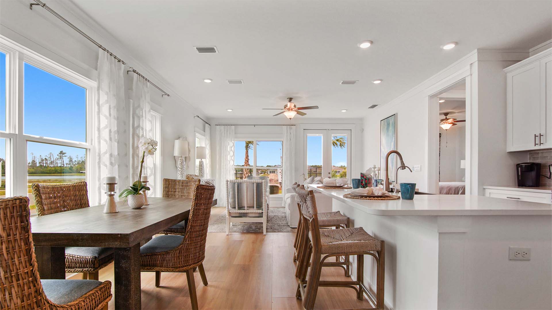 Open concept living area with kitchen and dining area and living room and EVP flooring and ceiling fan and large windows and glass double doors to back patio.