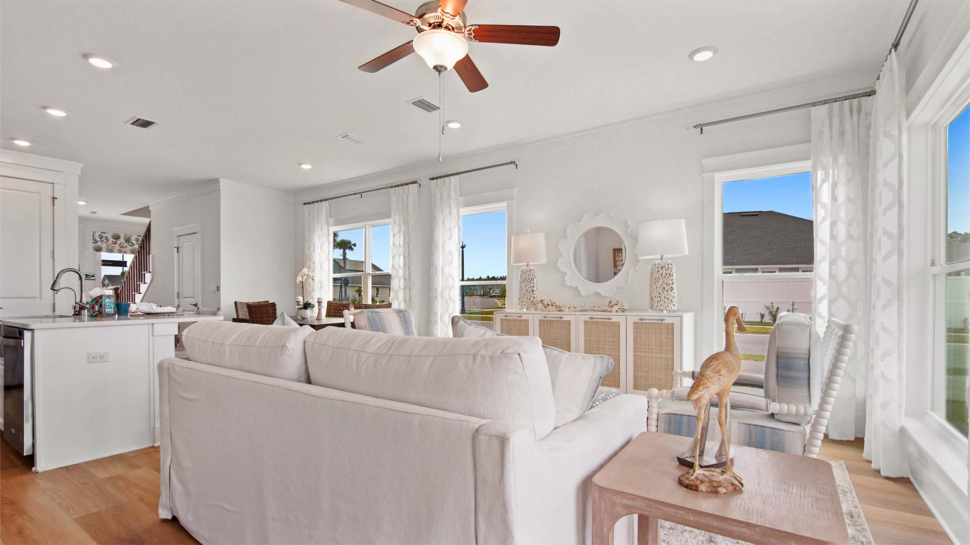 Open concept living area with multiple large windows and ceiling fan and EVP flooring.