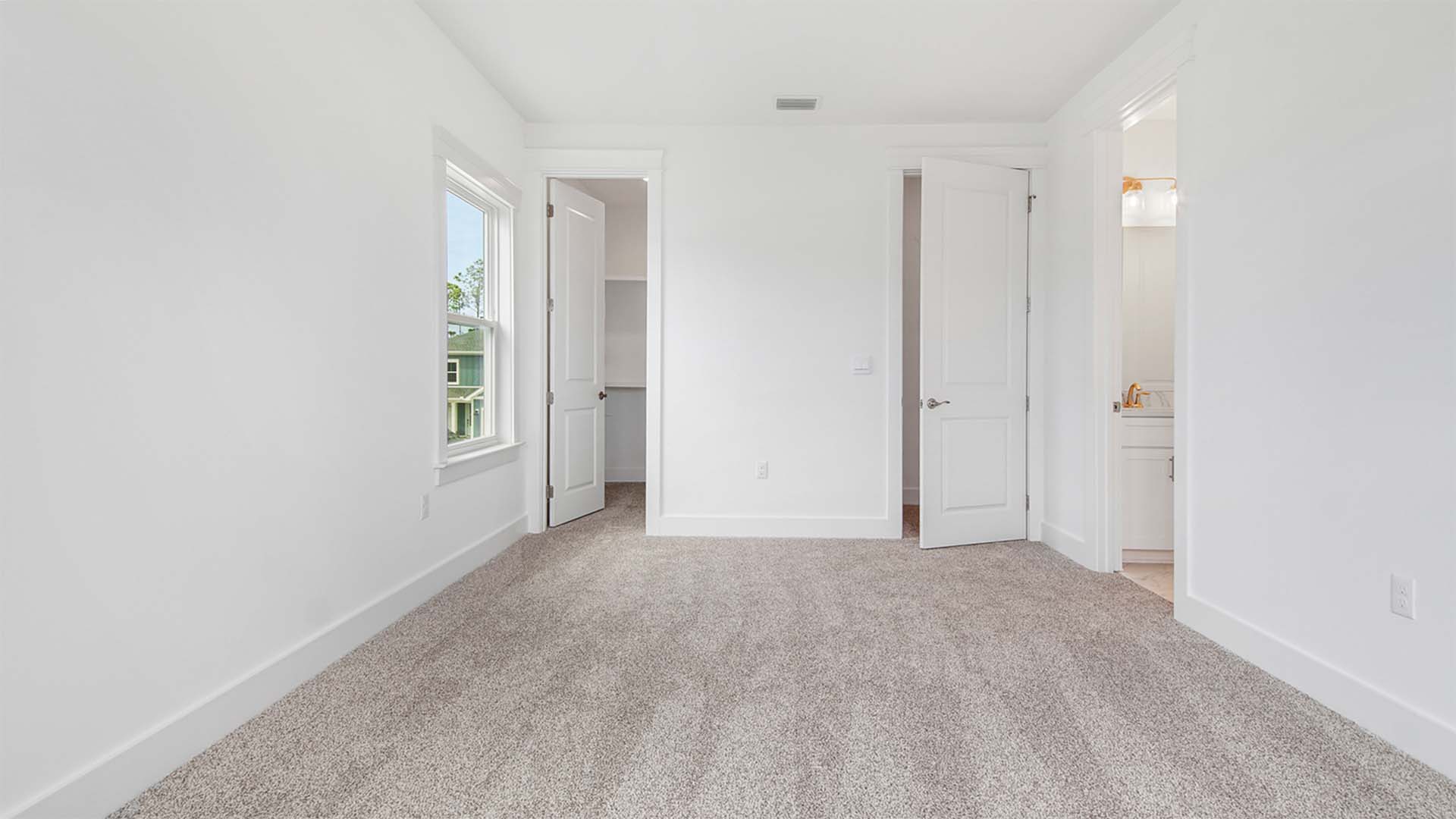 Bedroom three with carpet flooring and walk-in closet and entrance to jack and jill bathroom.