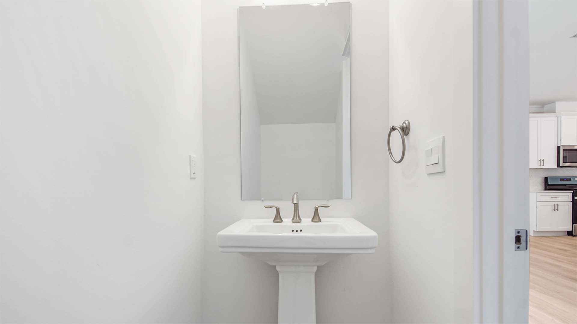 Half bathroom off foyer with pedestal sink.