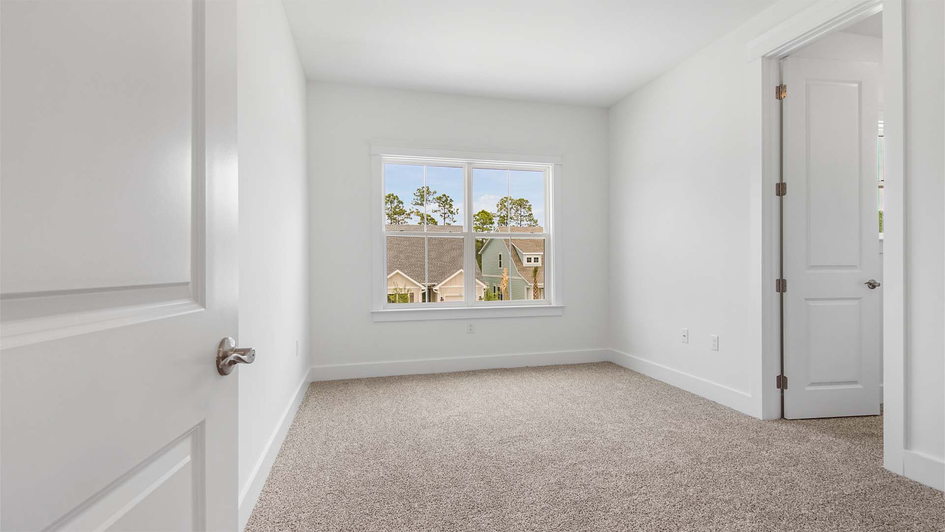 Bedroom five with a large window and carpet flooring and a large walk-in closet with a window and wood shelving.