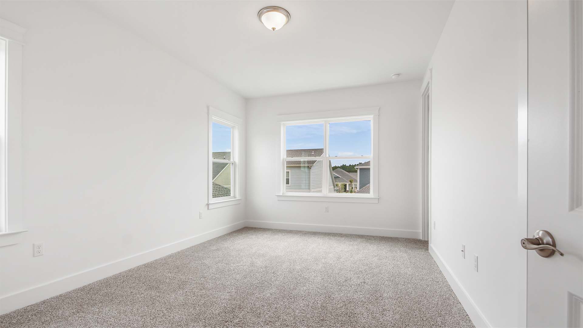 Bedroom two with carpet flooring and large windows and walk-in closet.