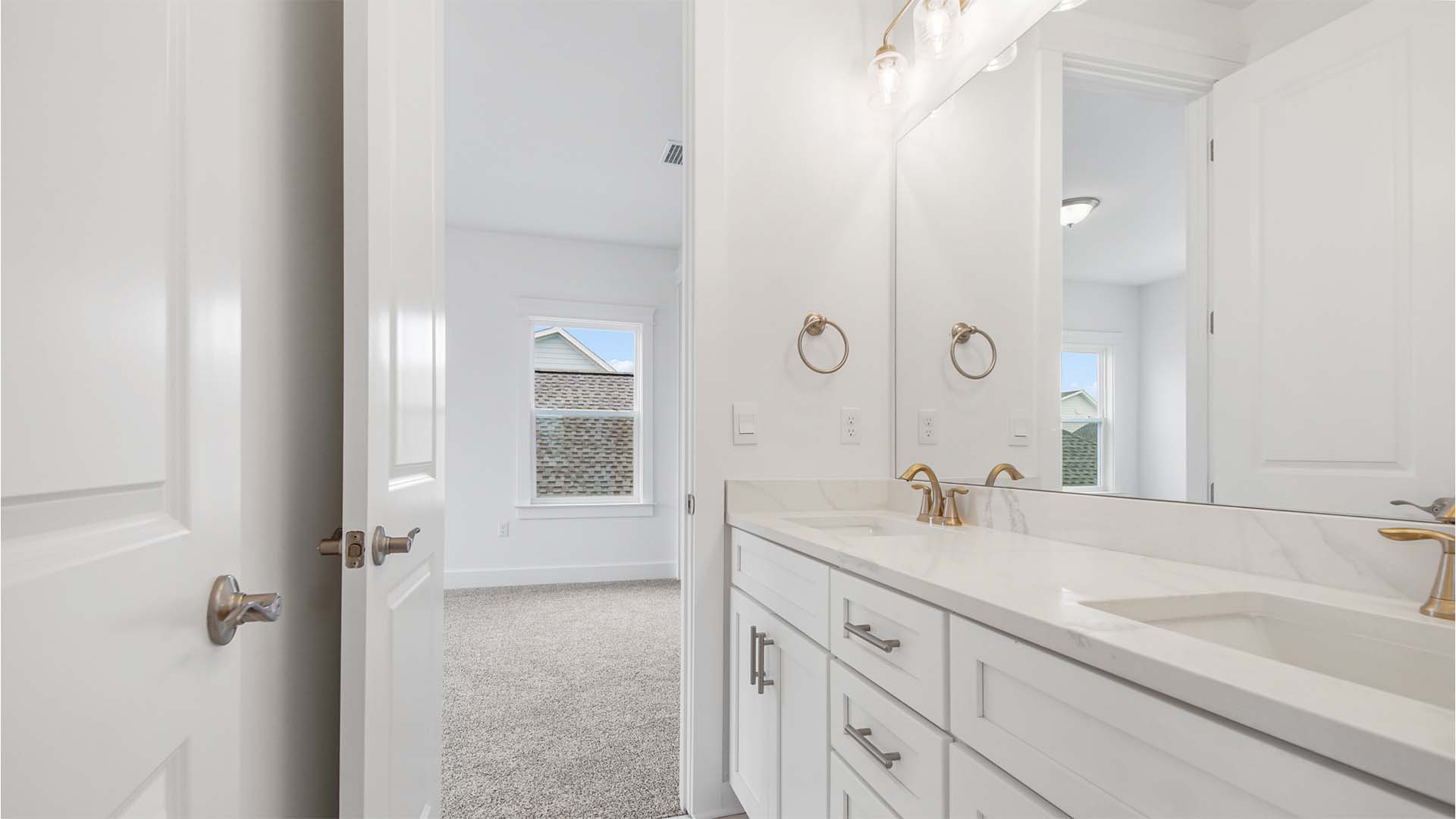 Jack and jill bathroom with dual vanity and quartz countertops and white cabinetry and a large mirror.
