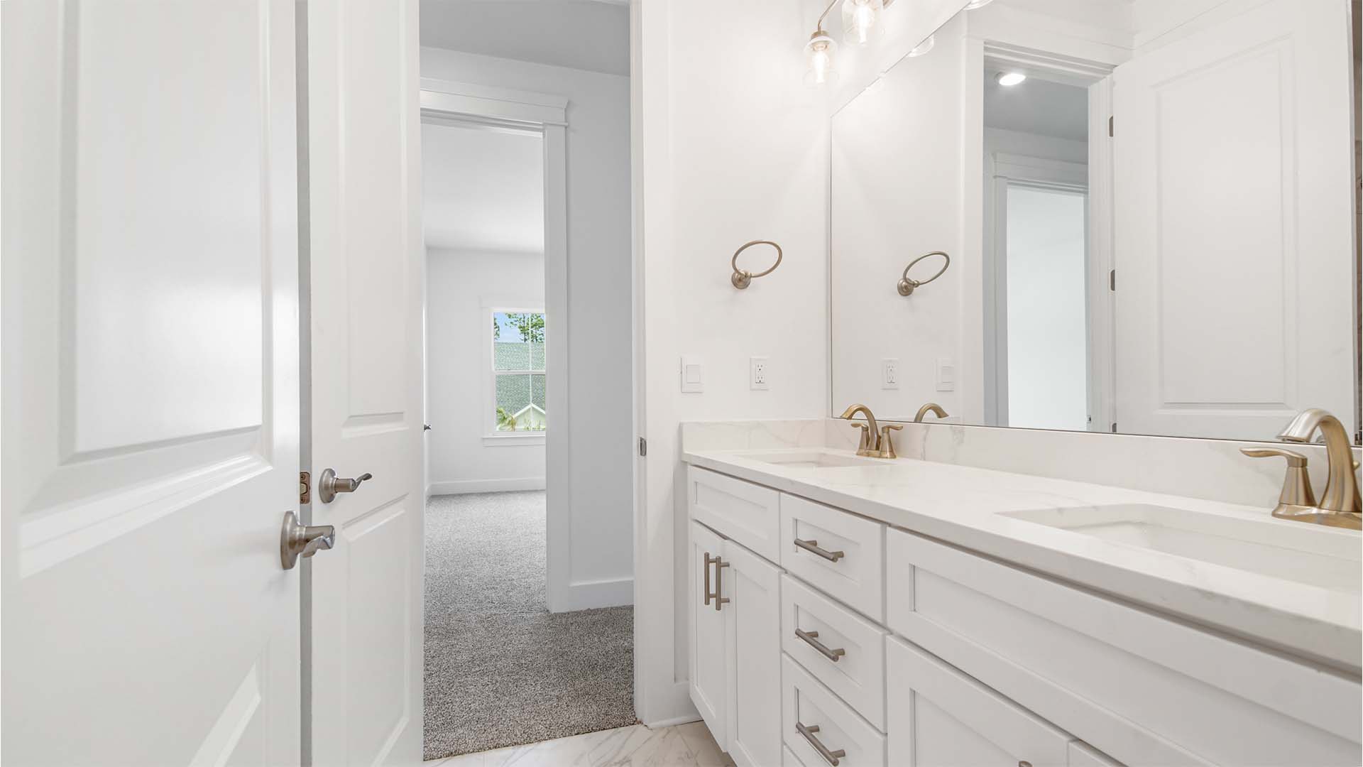 Bathroom three with dual vanity and quartz countertops and white cabinetry and a large mirror.