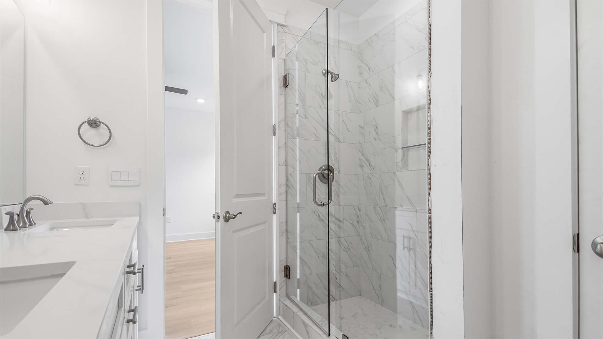 Primary bathroom with large tile shower with glass door.