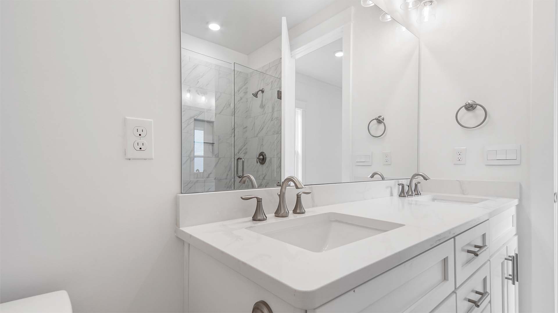 Primary bathroom with dual vanity and quartz countertops and white cabinetry and large mirror.