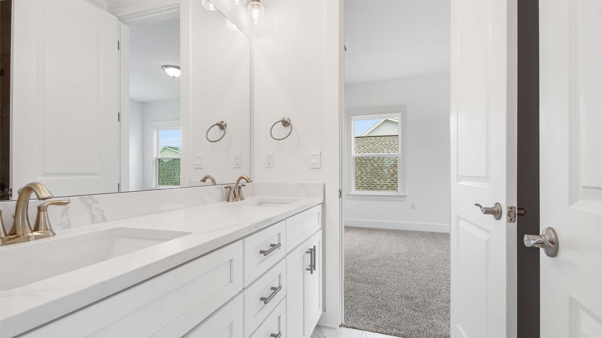 Jack and jill bathroom with dual vanity and quartz countertops and door to bedroom three.