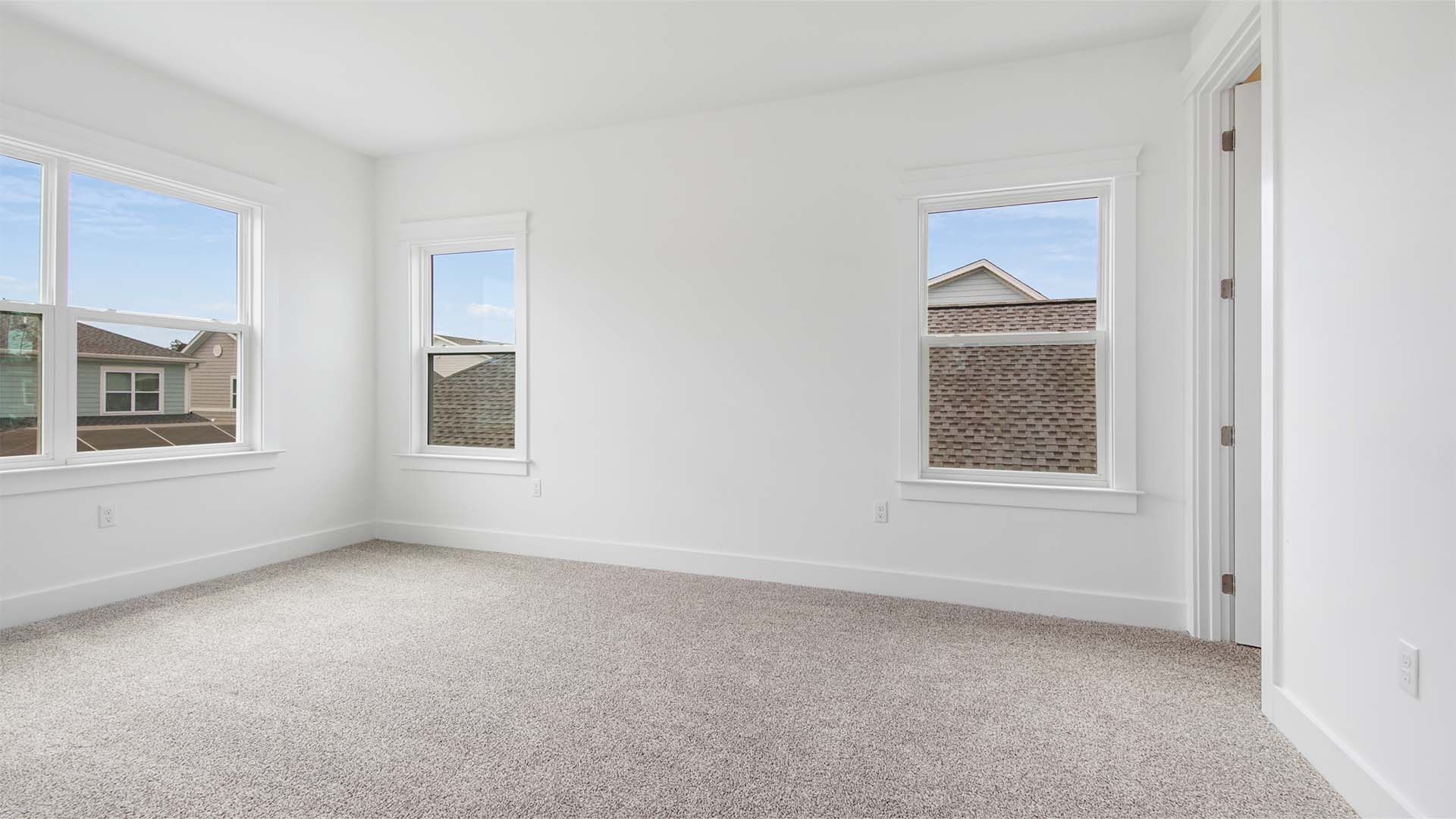 Bedroom three with large windows and carpet flooring and walk-in closet with wood shelving.