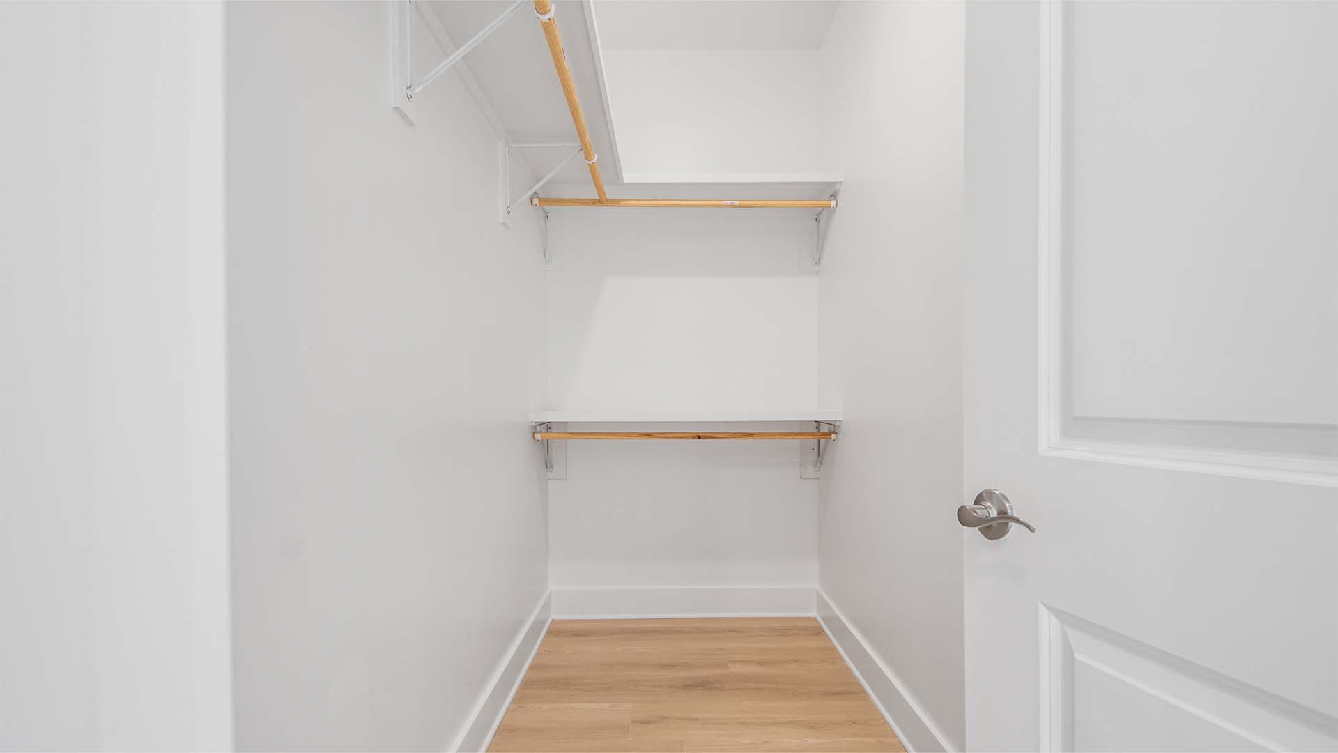 Large walk-in closet with EVP flooring and wood shelving.