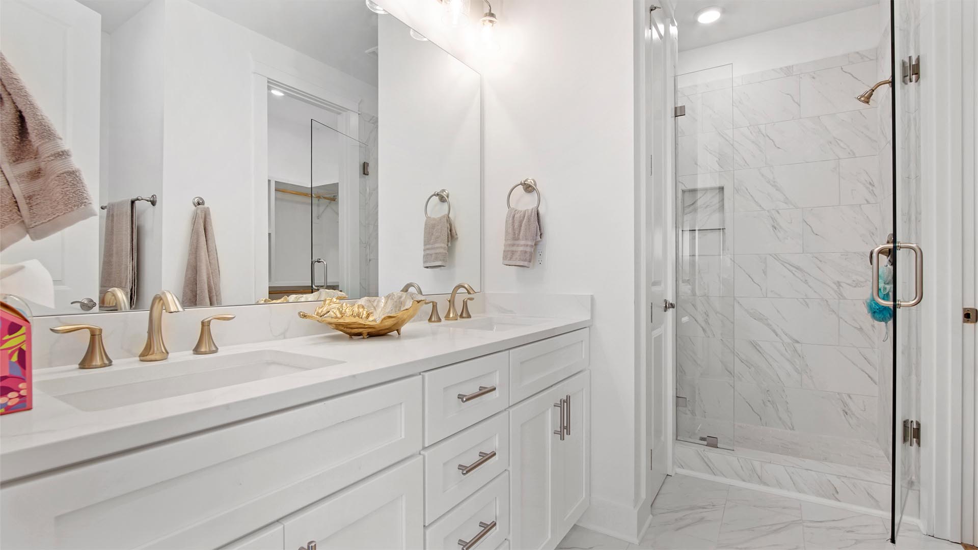 Breakfast Point Bluewater plan primary bathroom with two sink vanity with quartz countertops and large tile shower with glass door and tile flooring.