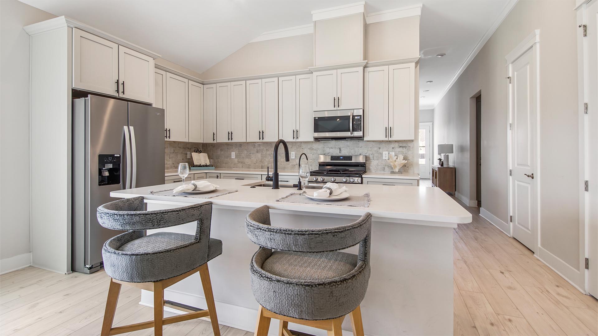 Breakfast Point Bluewater plan kitchen with island and bar seating and quartz countertops and EVP flooring and stainless-steel appliances.