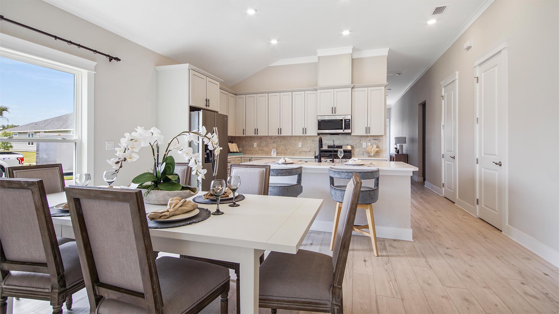 Dining area overlooking kitchen with EVP flooring and large windows.