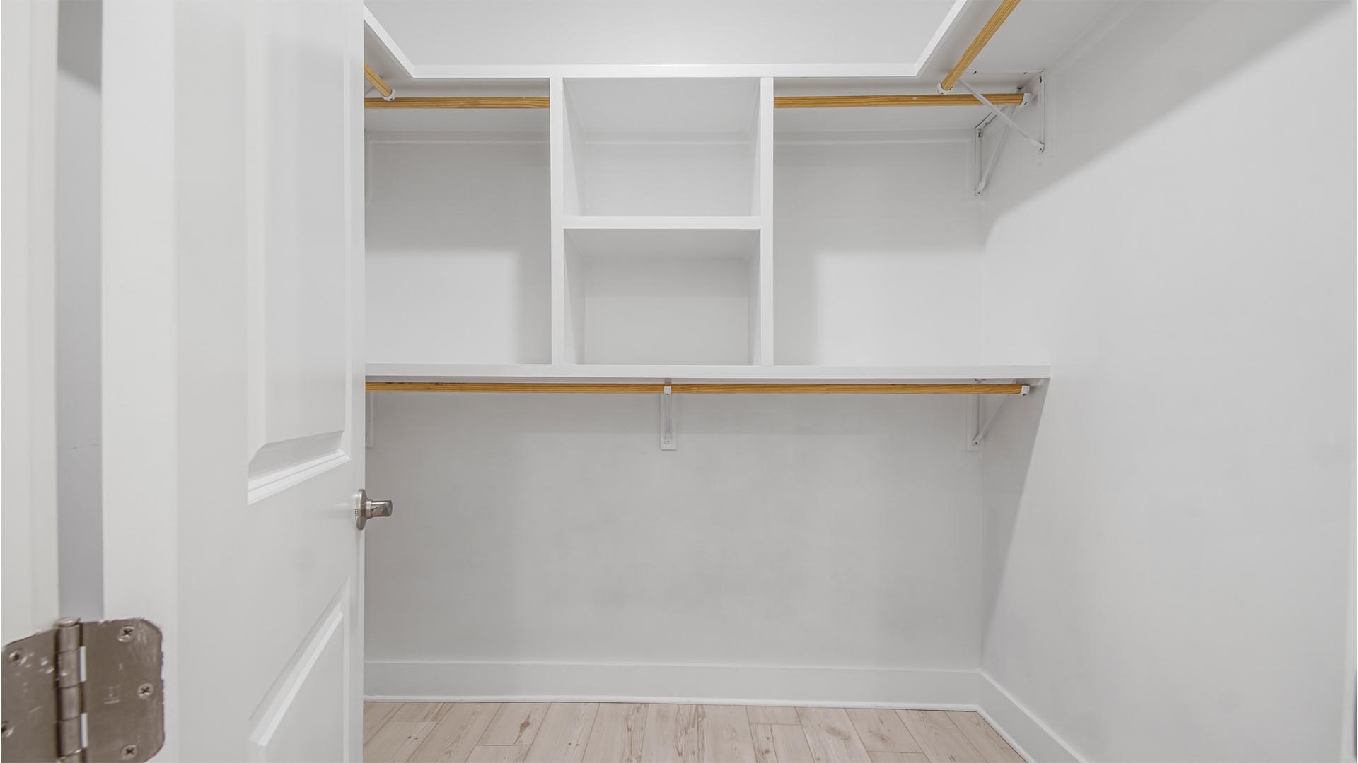 Primary closet with EVP flooring and wood shelving.
