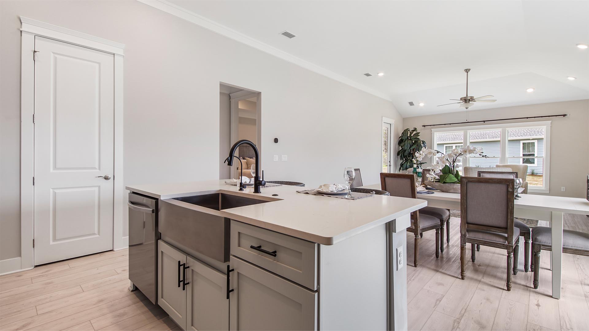 Large kitchen island overlooking living area with stainless-steel single basin undermount sink and dishwasher.