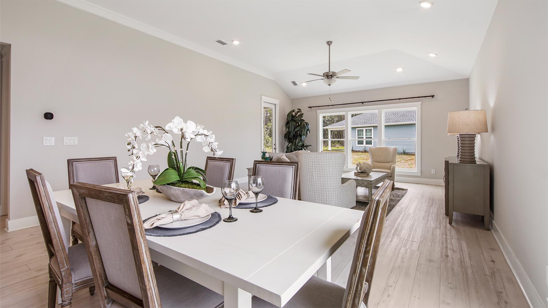 Open concept dining area overlooking living area with large windows and EVP flooring.