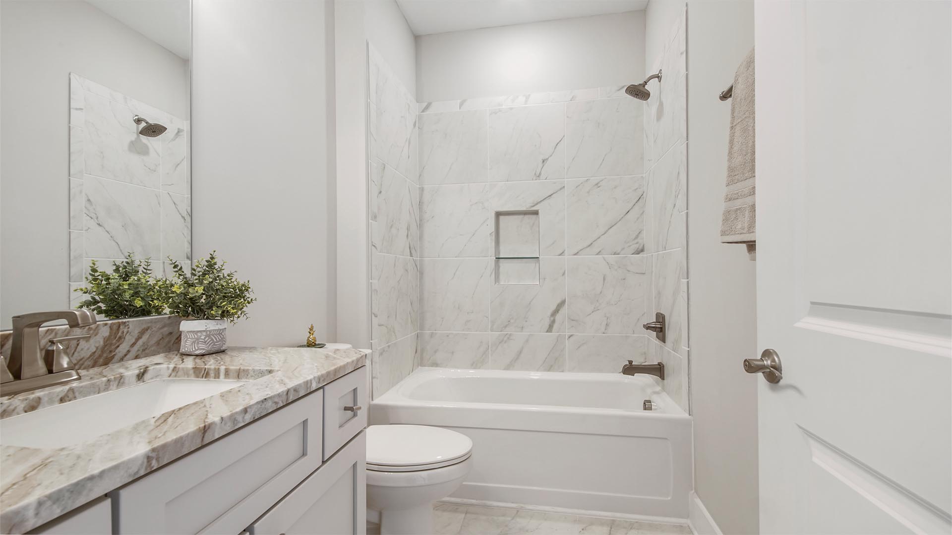 Bathroom two with tub shower with tile walls and marbled flooring and single vanity with quartz countertops.