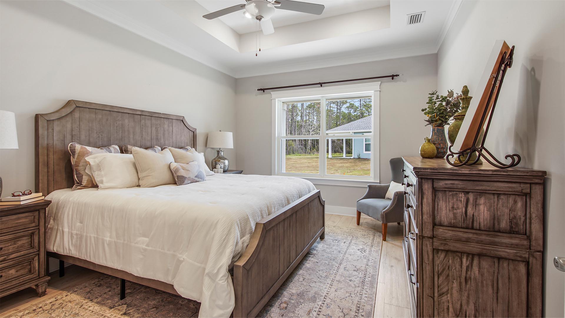 Primary bedroom with large picture window and vaulted ceilings and ceiling fan.