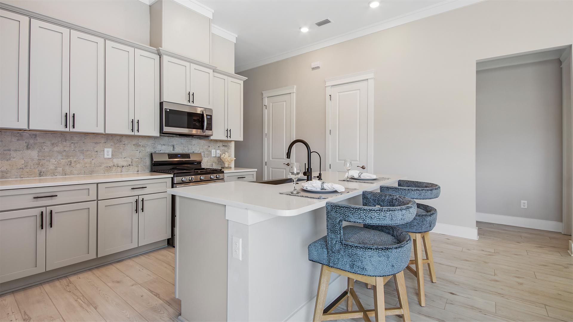 Bright open kitchen with island with bar seating and quartz countertops and EVP flooring.