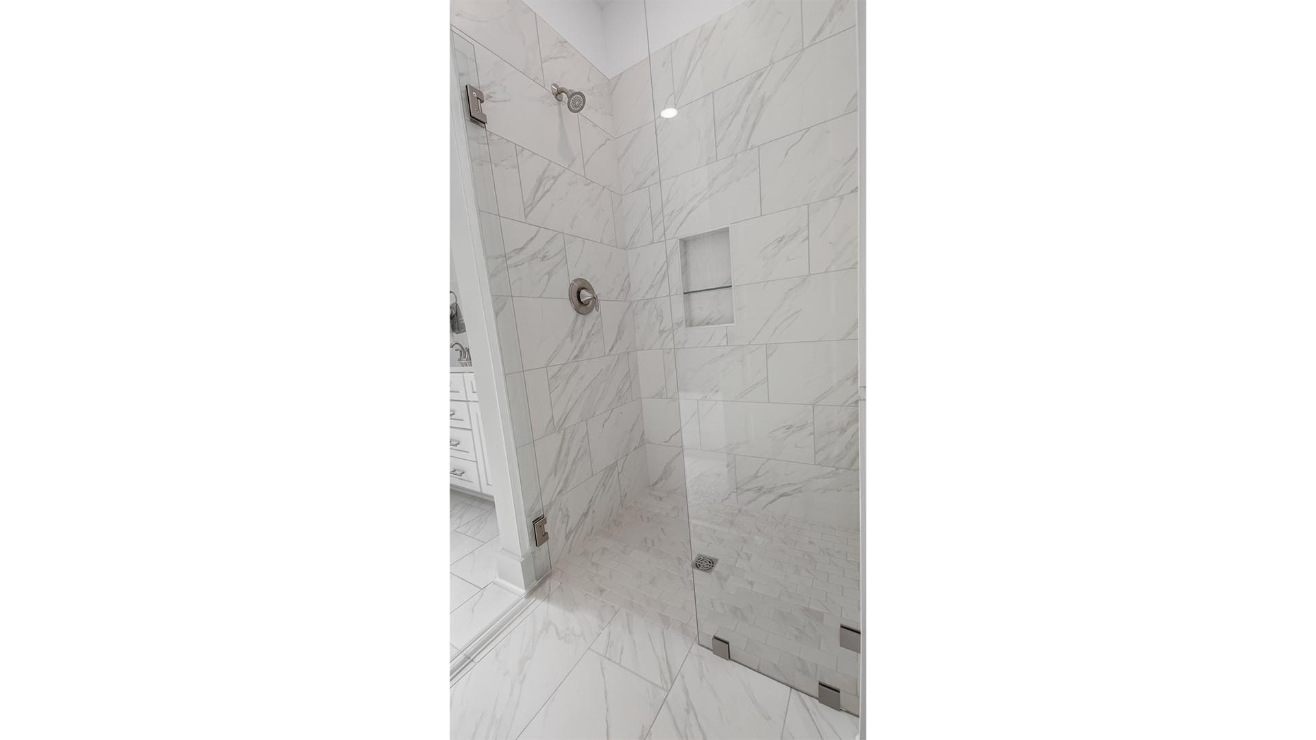 The large shower features beautiful tile and glass enclosure