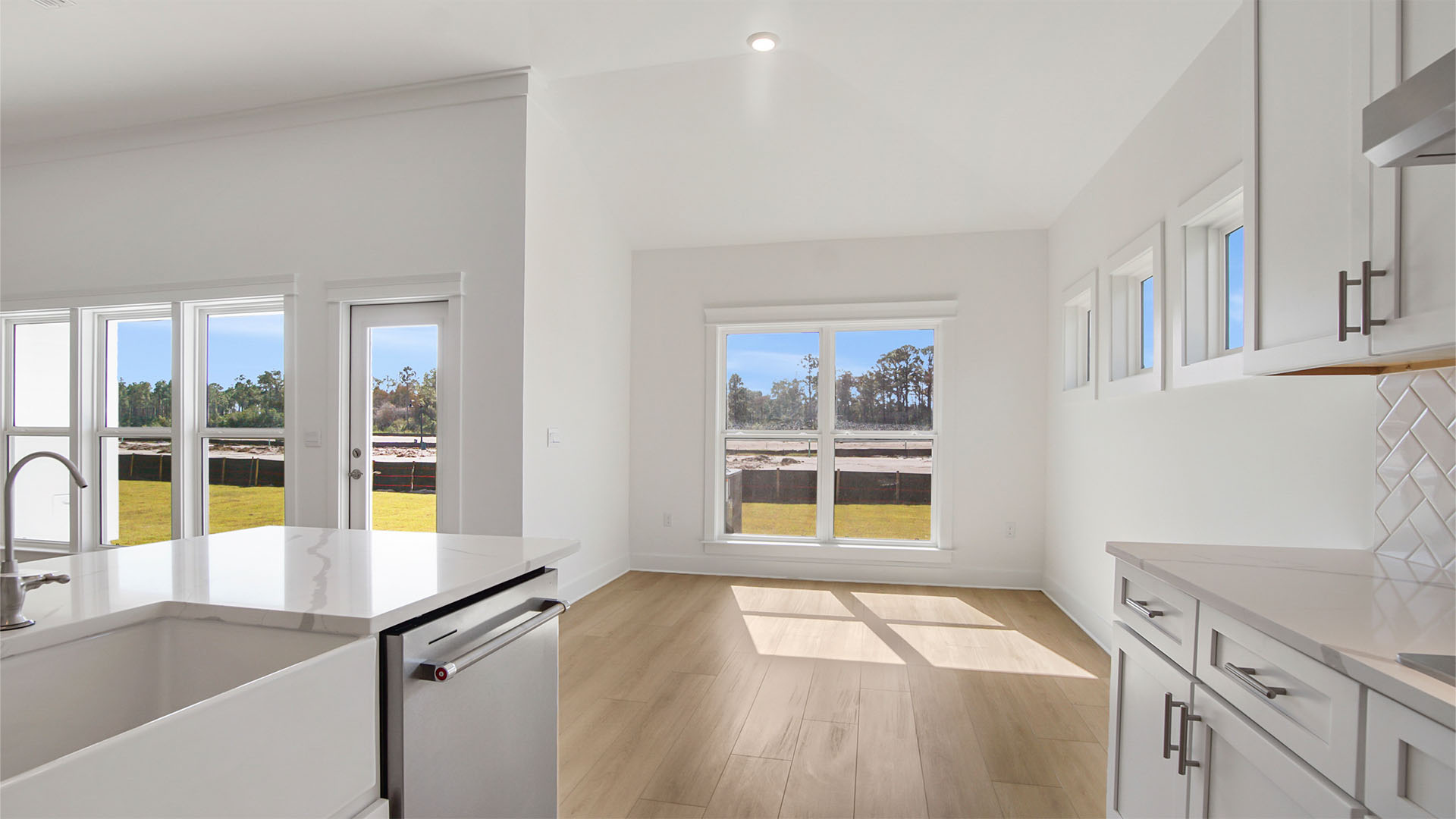 Open kitchen overlooking breakfast nook with large windows and EVP flooring.