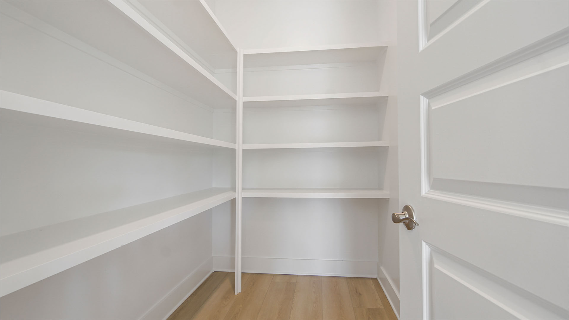 Large walk-in pantry with EVP flooring and wooden shelving.
