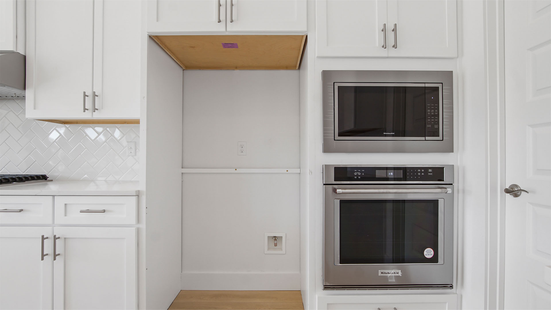 Bright kitchen with white cabinetry and quartz countertops and stainless-steel appliances.