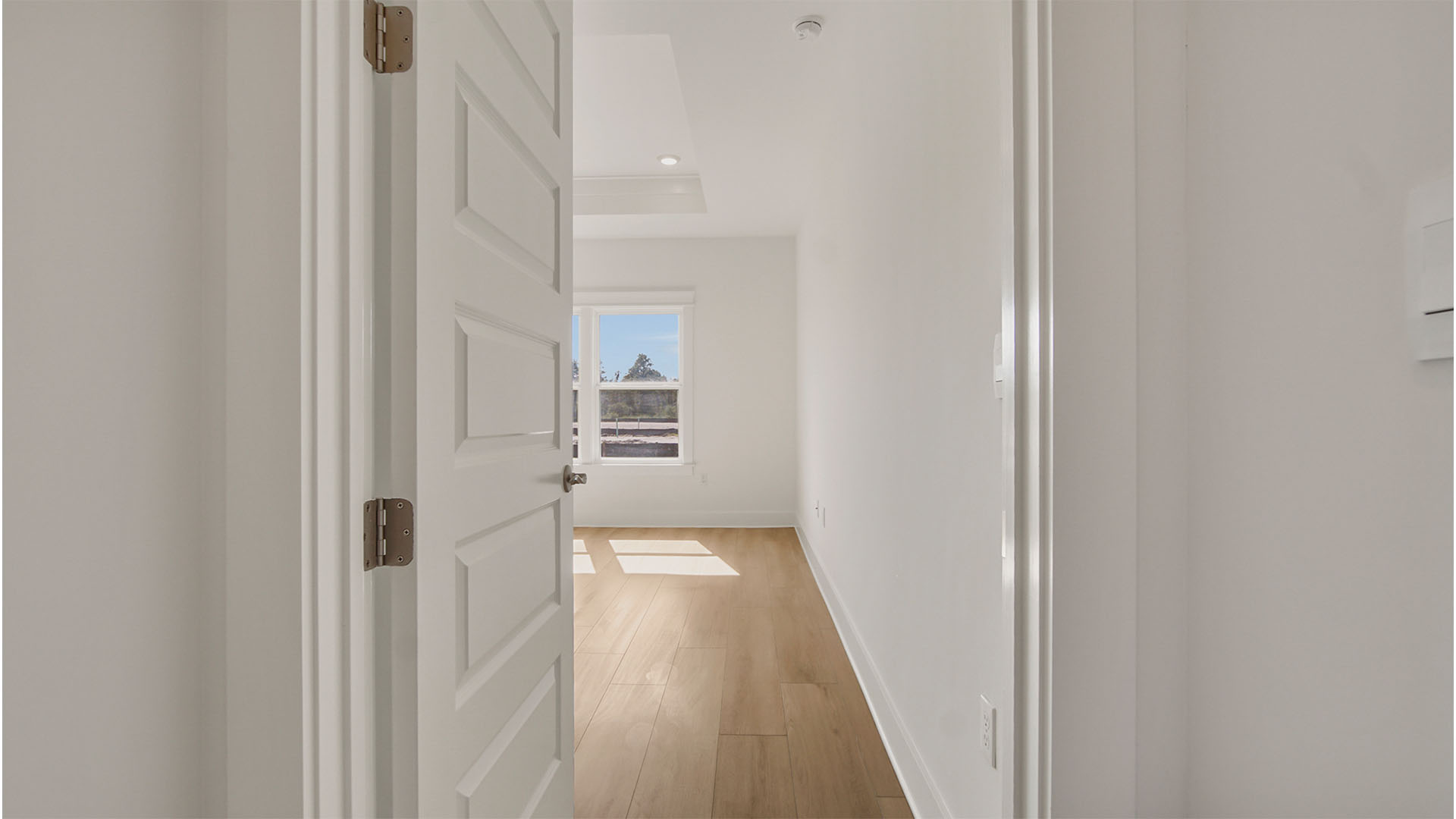 Door to primary bedroom with EVP flooring and white walls and door.