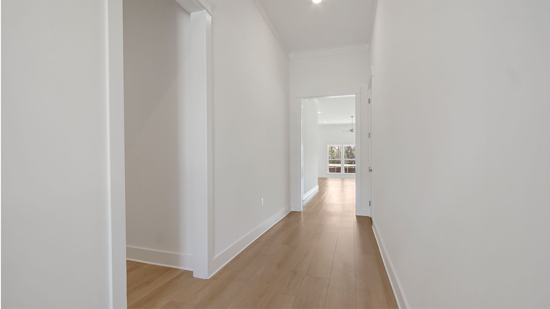 Foyer with tall ceilings and EVP flooring and hallway to guest bedrooms and entrance to living area.