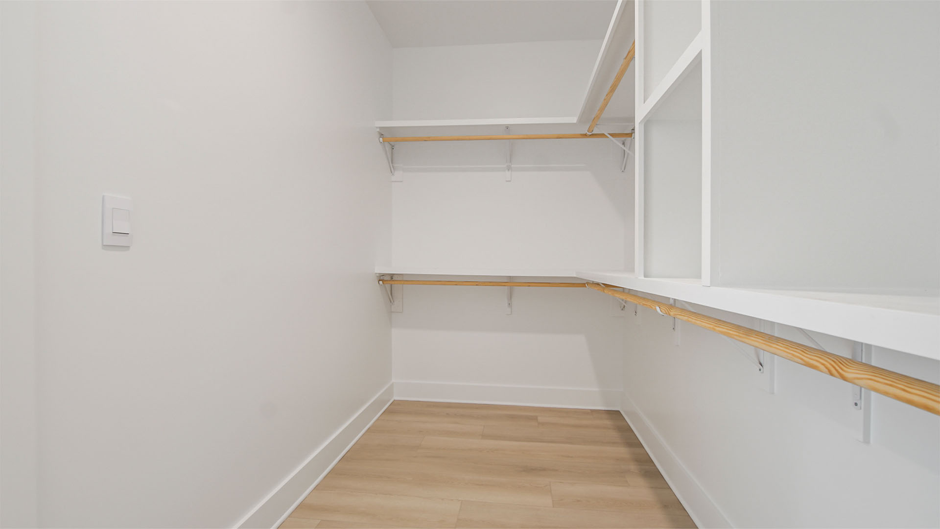 Large walk-in primary closet with wooden shelving and EVP flooring.