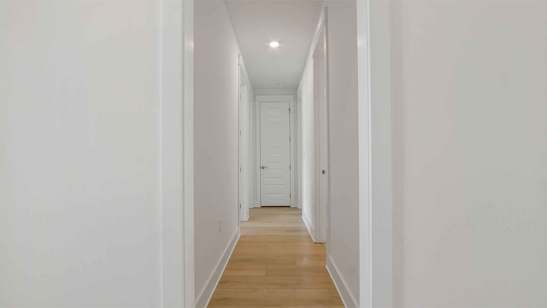 Hallway off foyer to guest bedrooms with EVP flooring and tall ceilings.