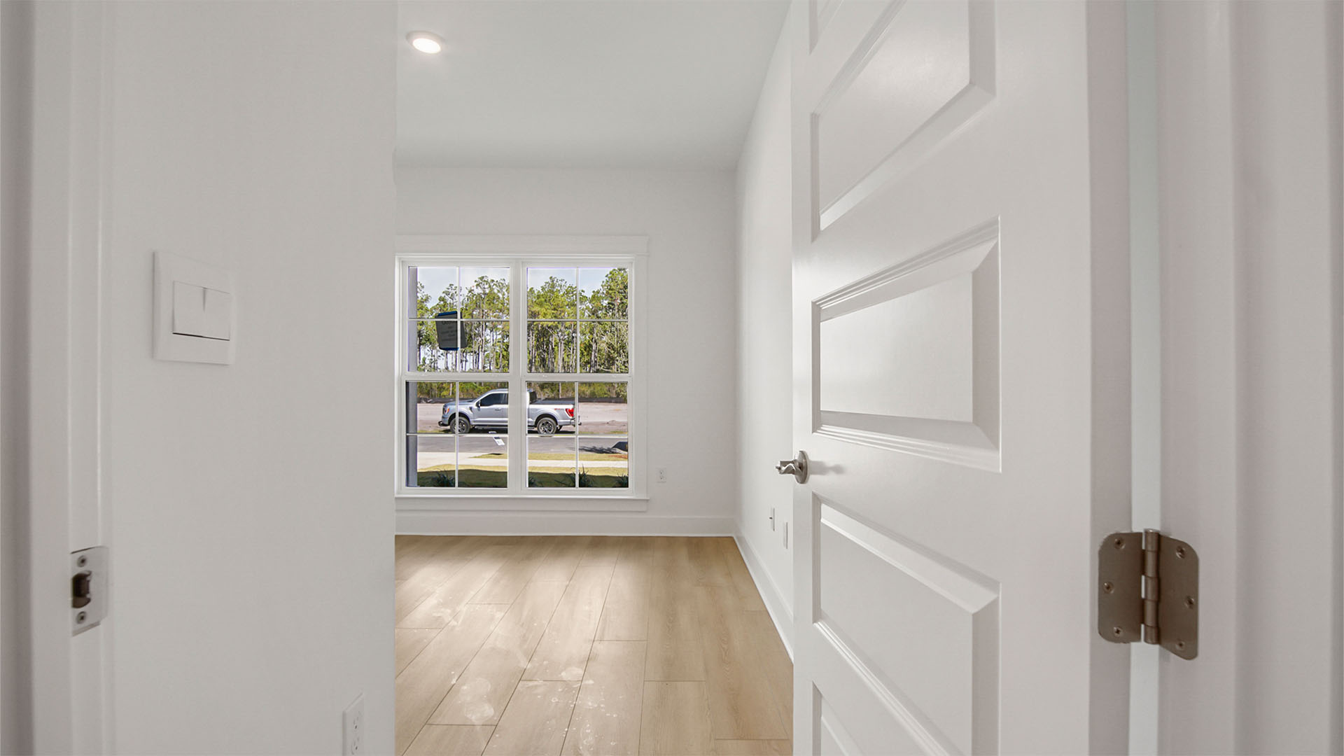 Bedroom two with large windows facing front of home with EVP flooring and tall ceilings.