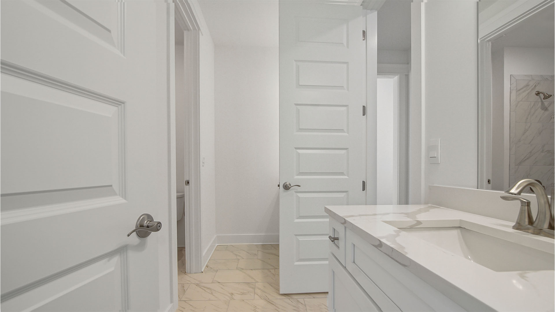 Bathroom two with marbled tile flooring and door to hallway and vanity with quartz countertops and white cabinetry.